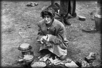 An emaciated woman cooking a meal of sorts